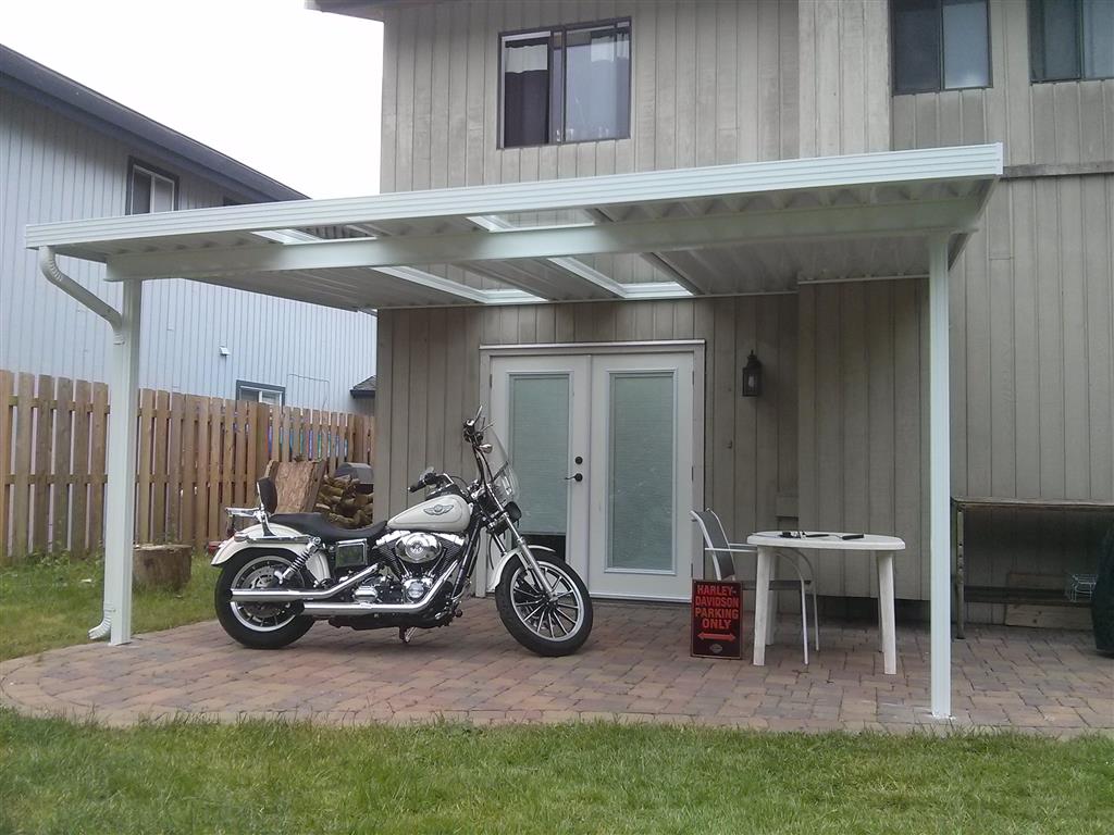 Aluminum canopy with skylights for outdoor motorcycle coverage. White panels, white trim, and white posts.