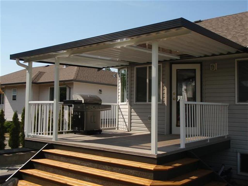 Aluminum canopy with skylights for outdoor barbeque with white panels, black trim and white posts.