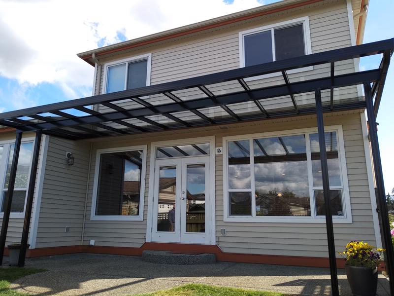 Glass patio cover with black trim and black posts.