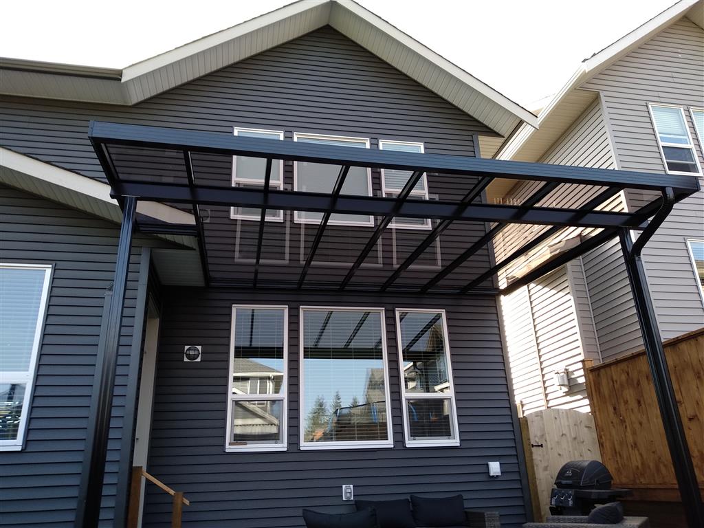 Glass patio cover with black trim and black posts.