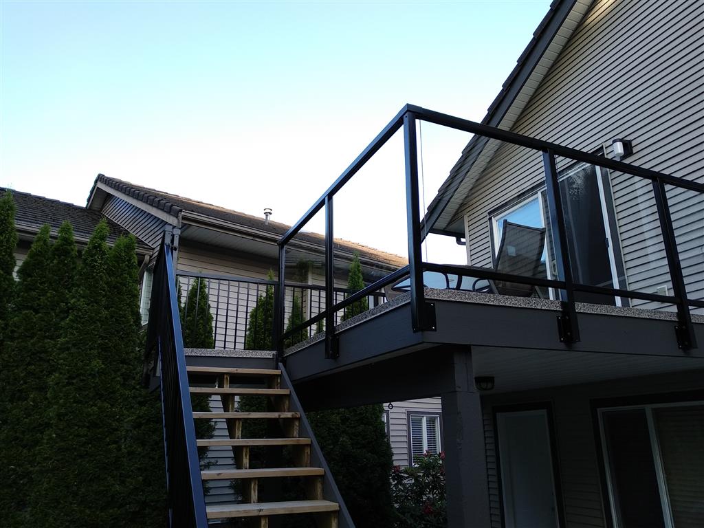 Glass railings with black trim at front side of deck and black aluminum railings at back side of deck and for staircase.