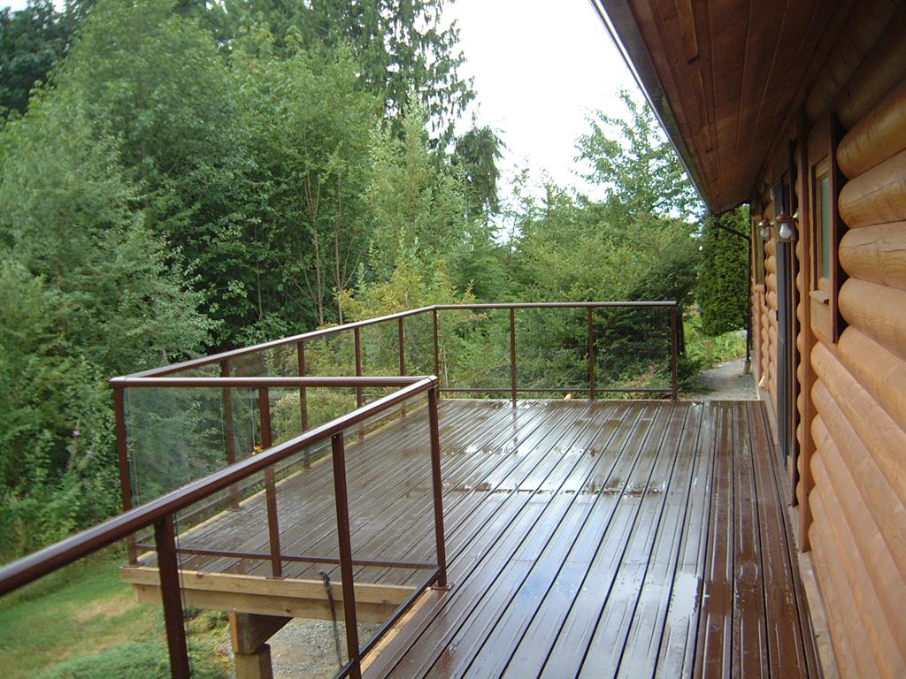 Glass railings with brown trim to complement log cabin home.